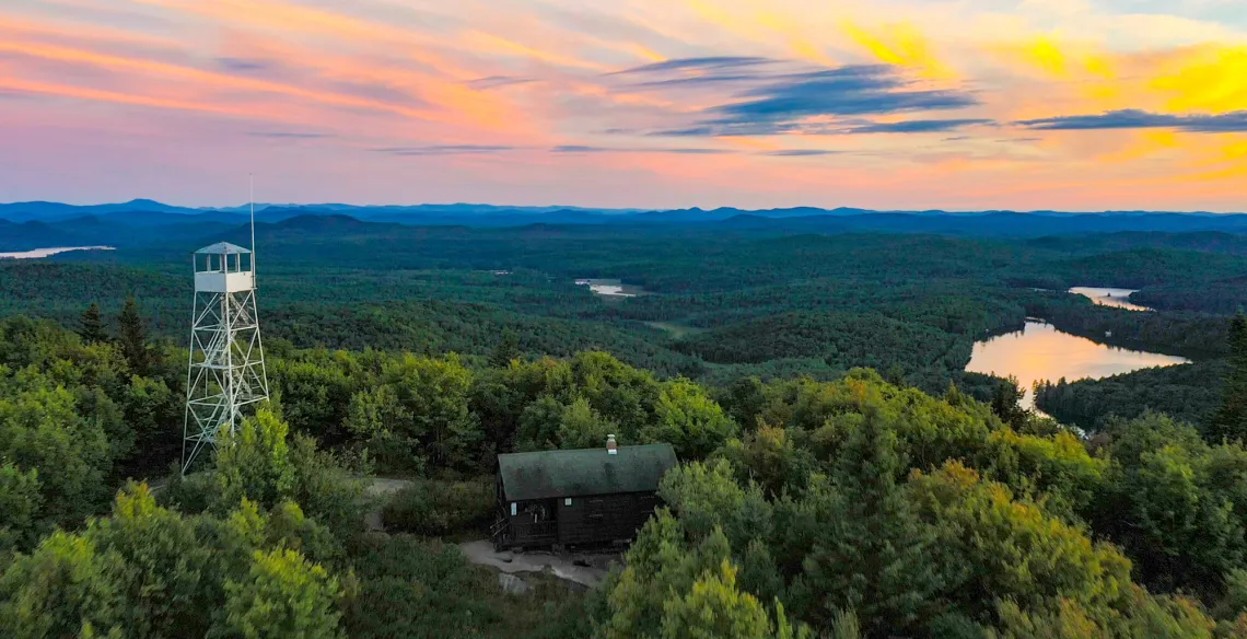 An aerial view of a fire tower looking out over an expansive forest.