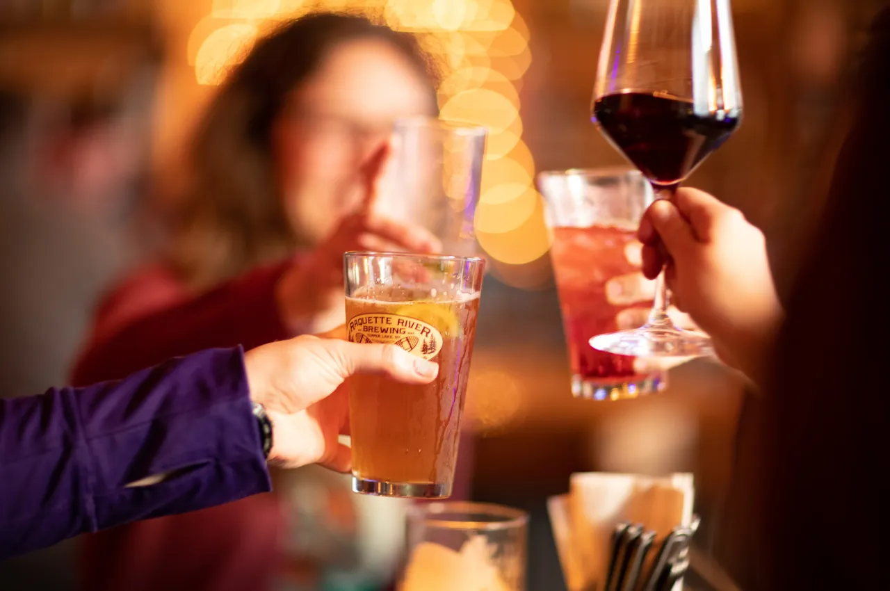 A close-up of four hands clinking drinks together.