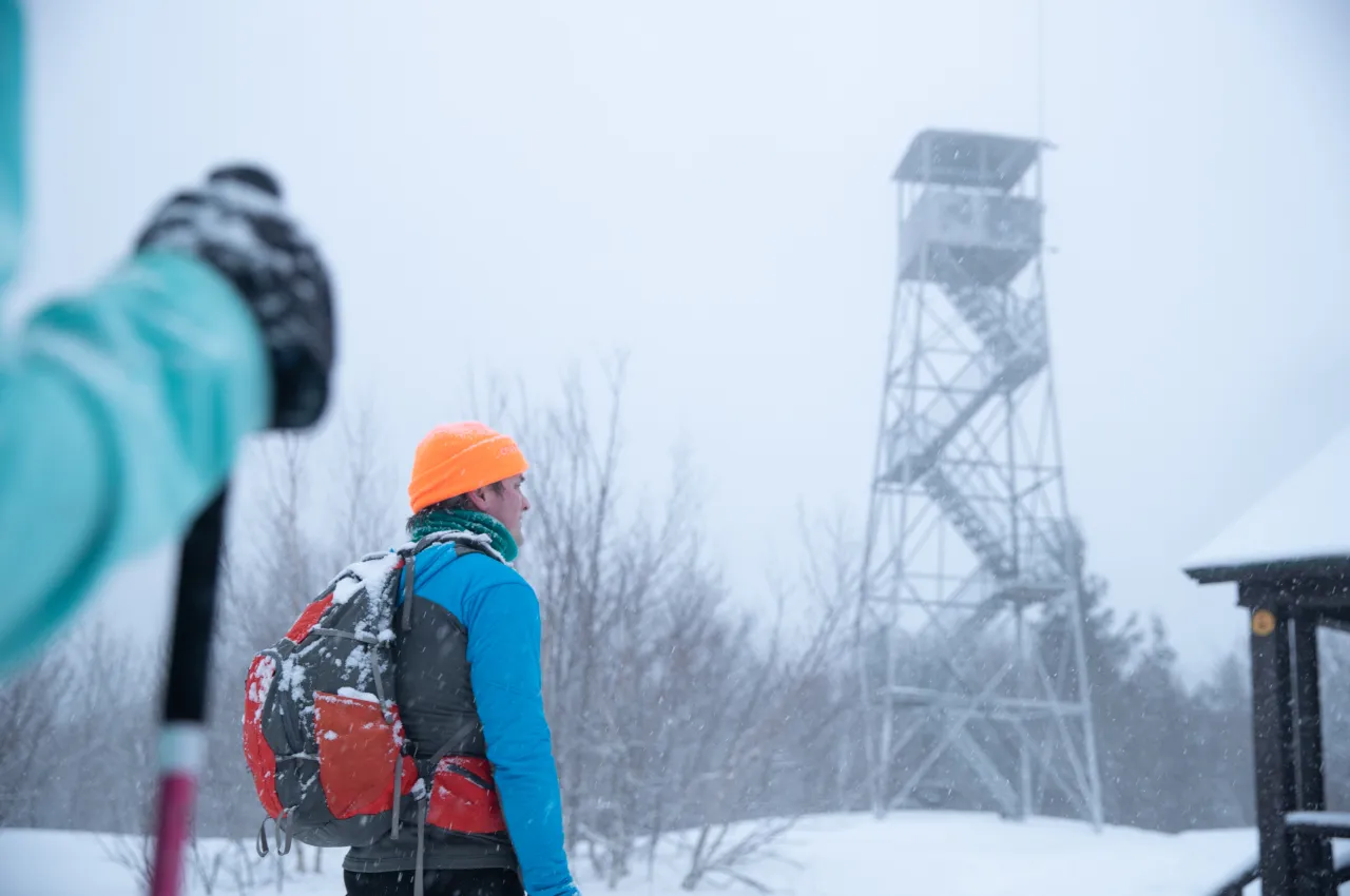 A man approaches the summit of Mt Arab with the fire tower in the background.