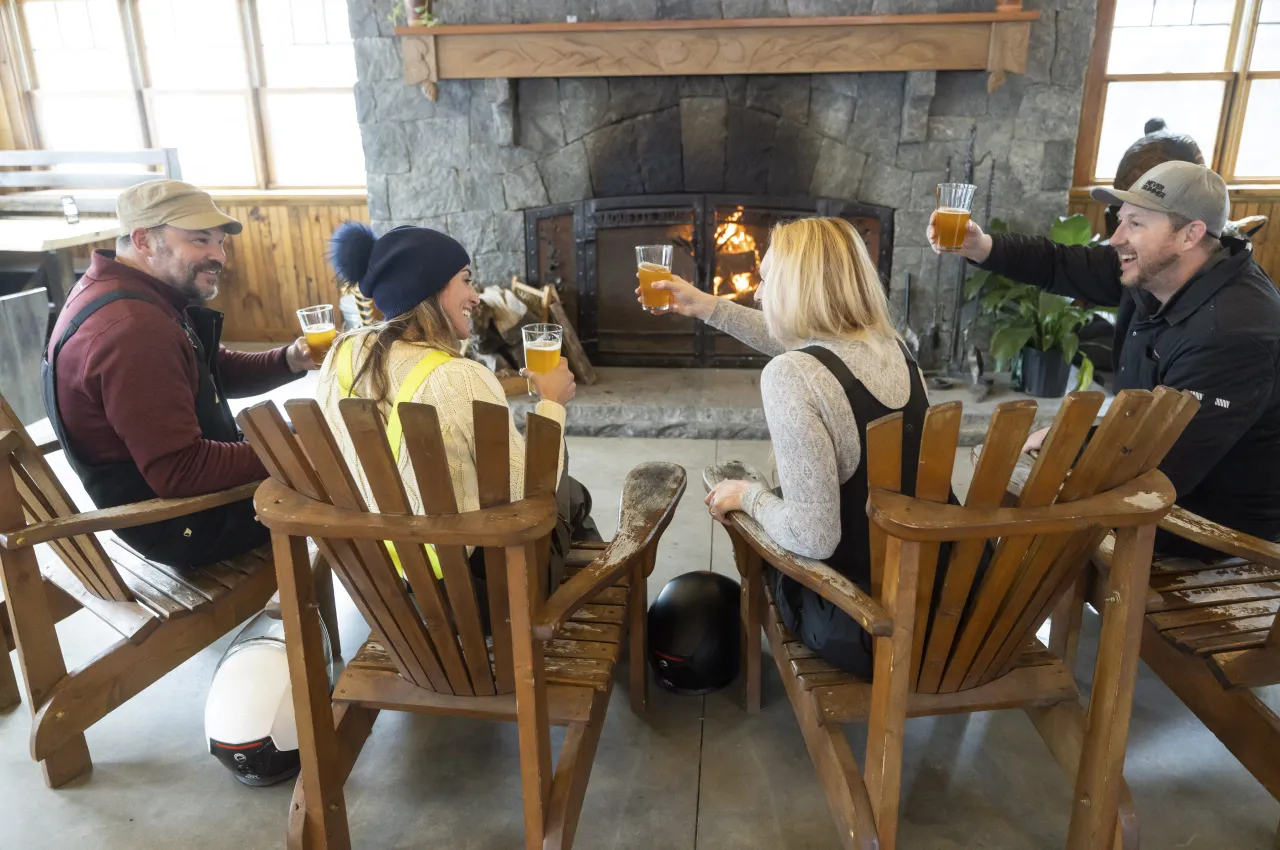 A group of friends having a craft beer by the fireplace at Raquette River Brewing.