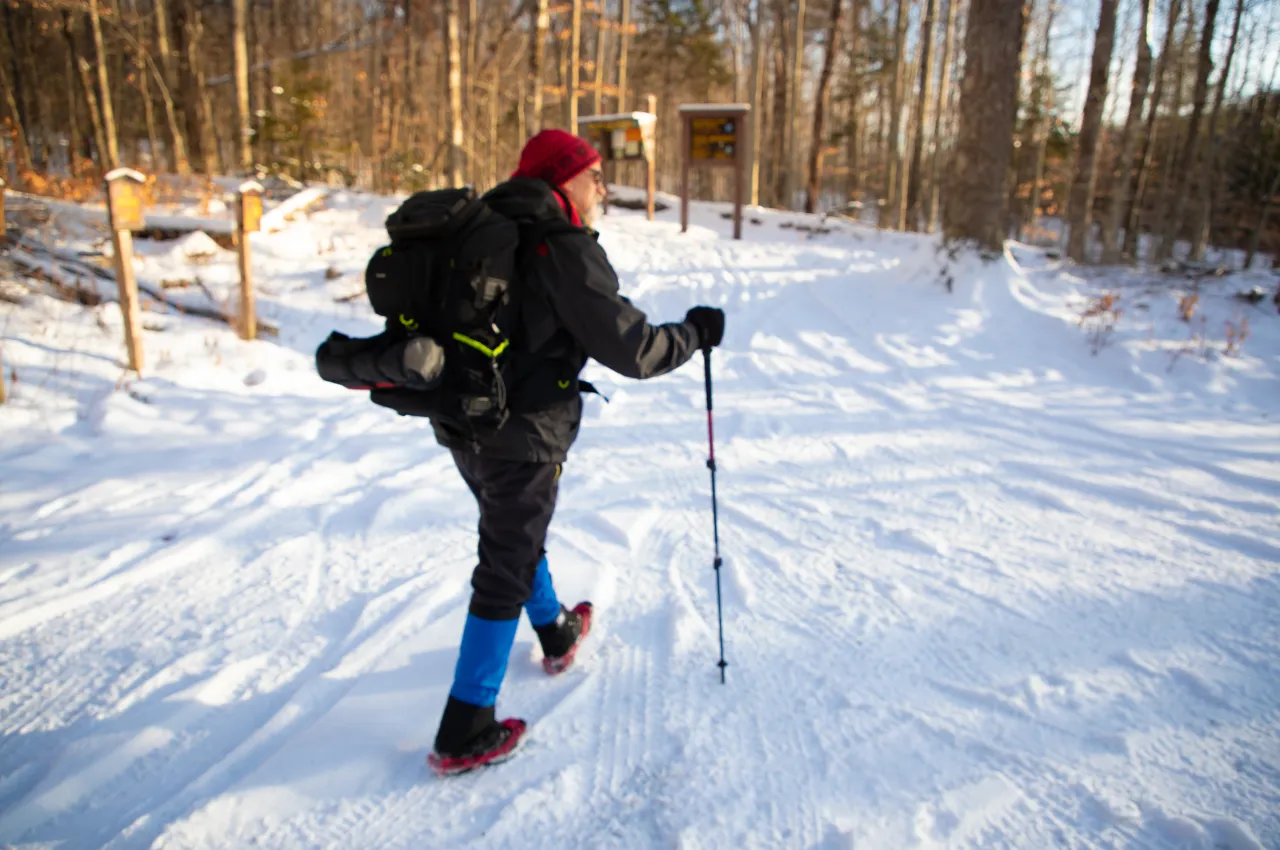 A man hiking in the winter approaches the trail.