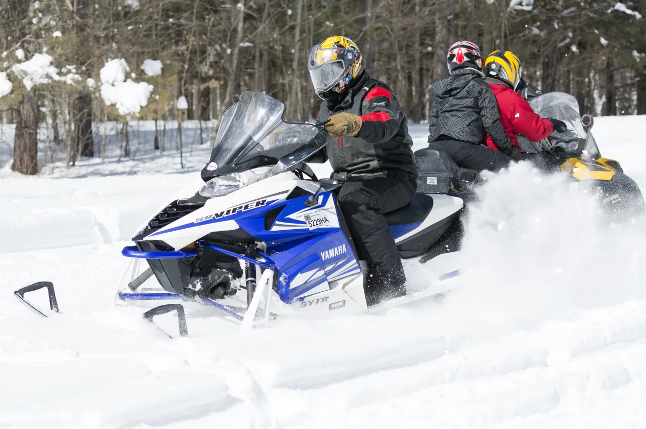 Snowmobilers pass eachother on the trail.