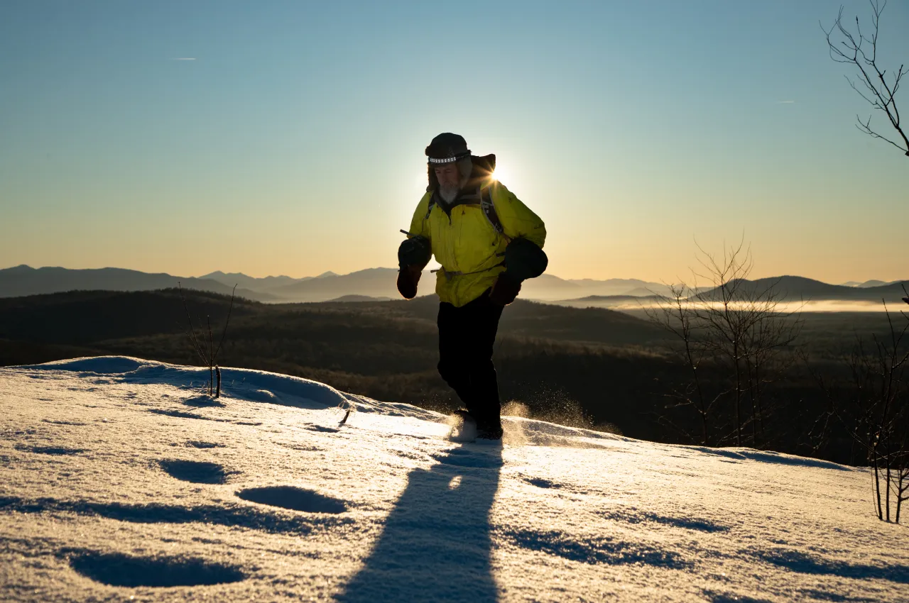 A hiker approaches the summit on snowshoes.