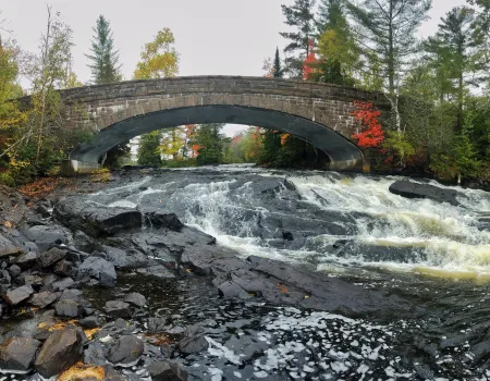 The arching bridge over Bog River Falls