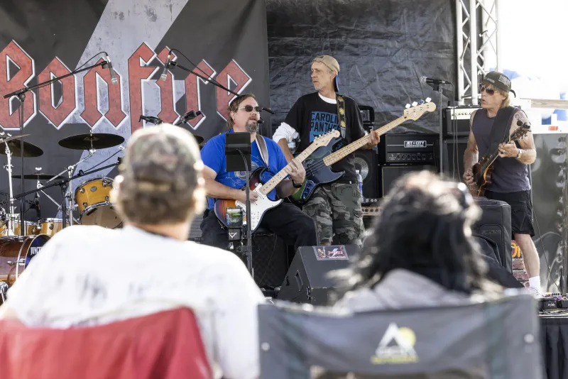 A band plays for a crowd at a rock concert during the day.