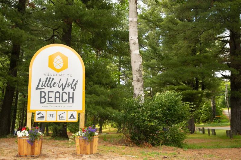 A sign with "little wolf beach" on the side.