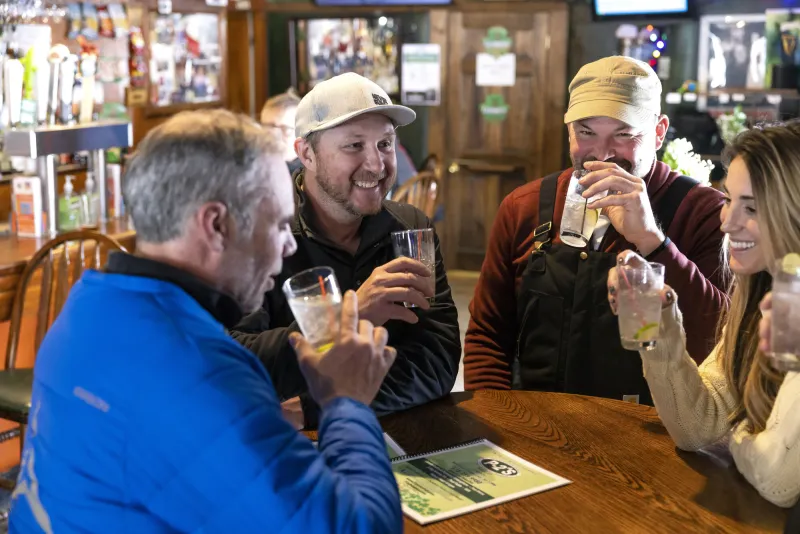 A group of men and women share beers at a pub.