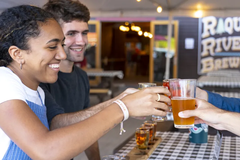 A man and woman cheers their drinks with friends.