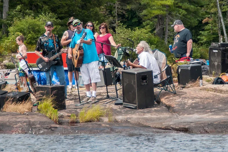 A band plays on a rock surrounded by water.