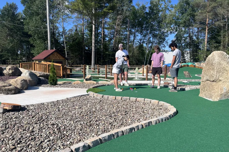 A family enjoys a game of mini golf on a sunny summer day.