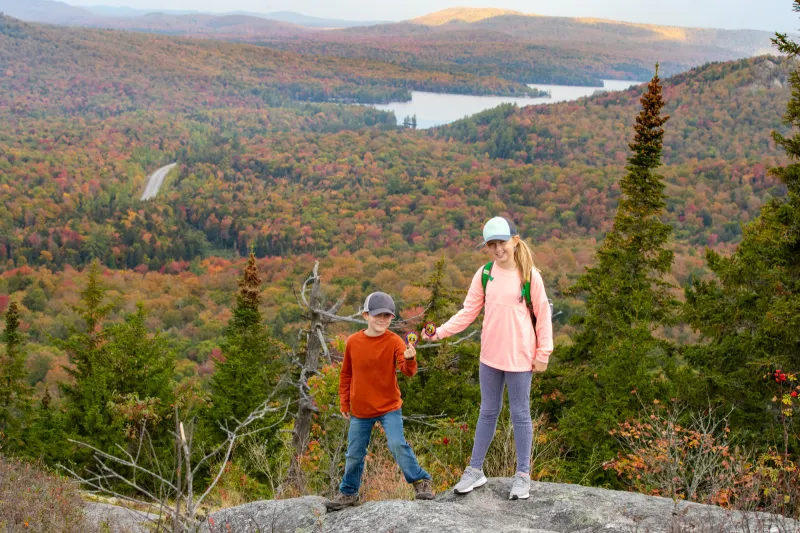 A couple kids in front of a scenic fall mountain view