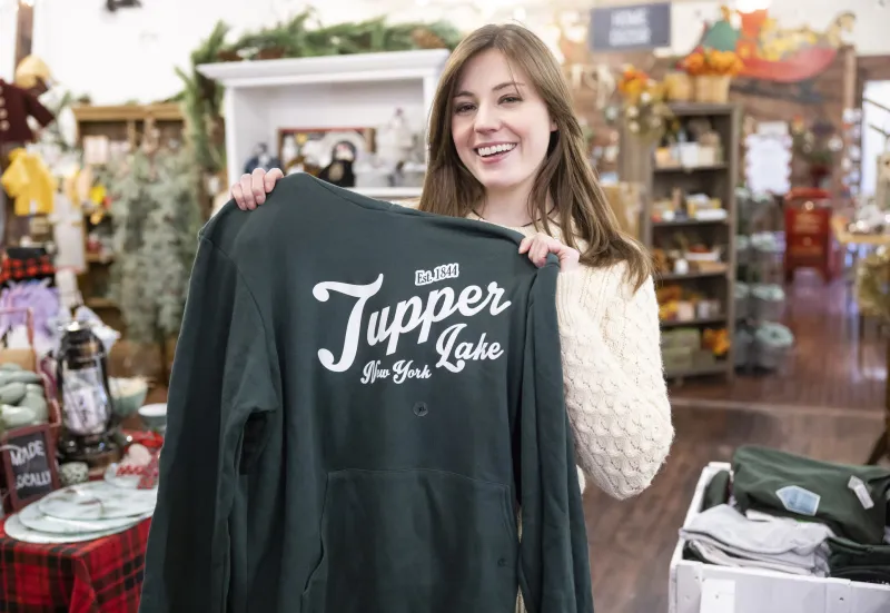 A woman holds up a Tupper Lake, NY shirt