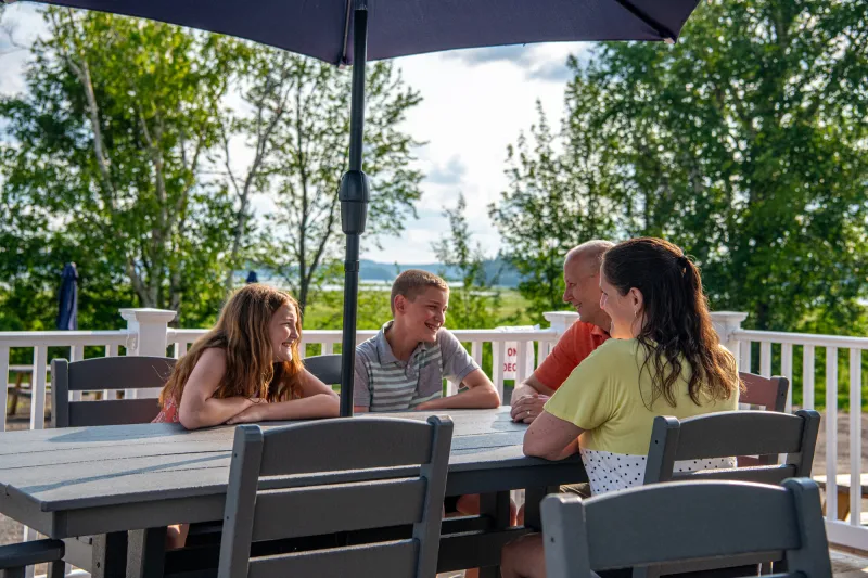 A family laughs at a picnic table.