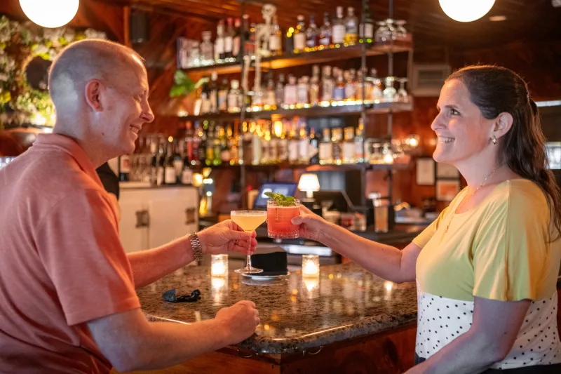 A man and woman clink drinks.