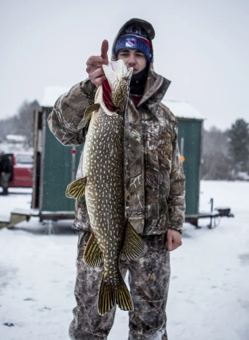 A man weighs in a large fish at the Northern Challenge Ice Fishing Derby