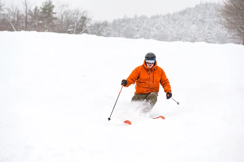 A man downhill skiing on a powder day.