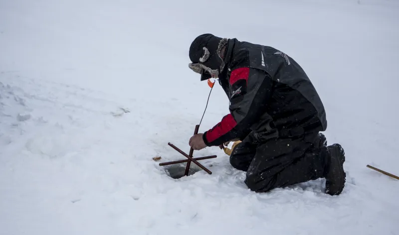 A fishermen checking his tip up.