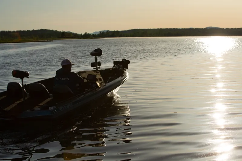 A fisherman on a motorboat heads out in the early morning sun.