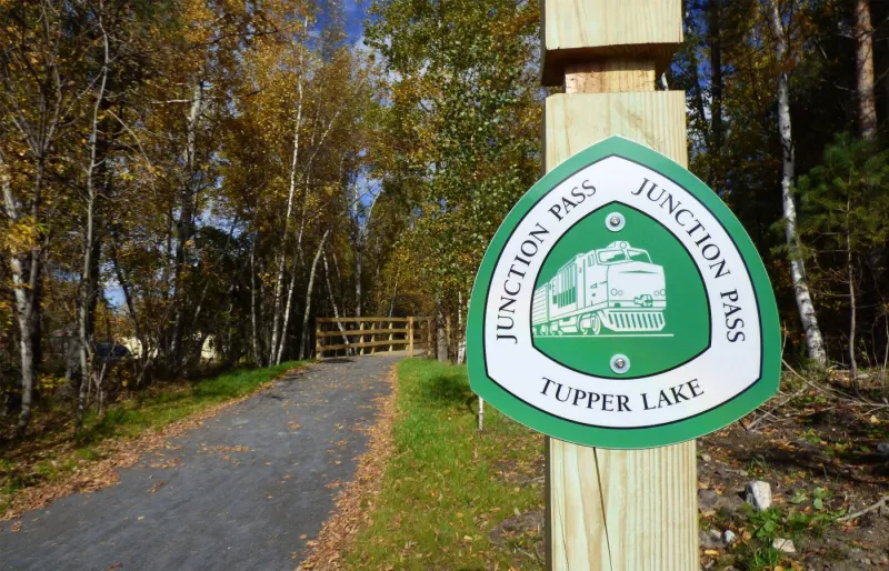 Trail sign for the Junction Pass Trail and the smooth gravel path in the background.