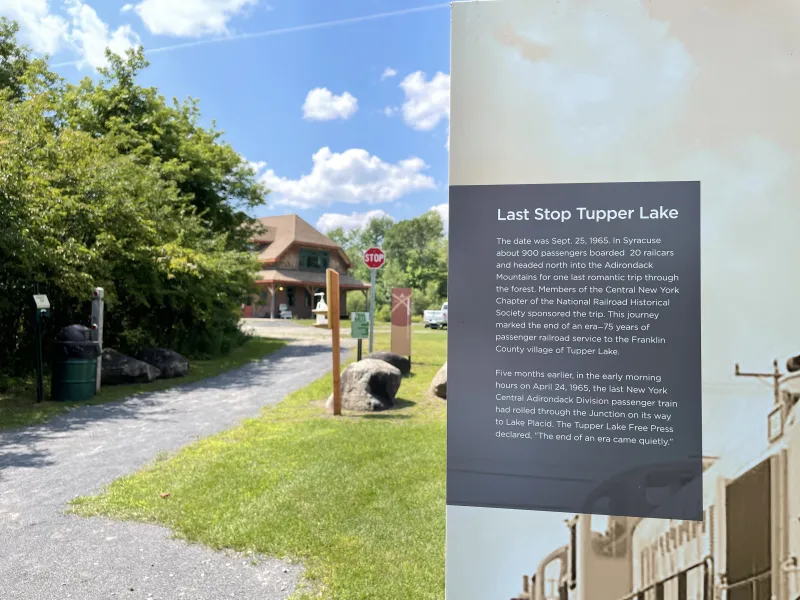 A sign explains local history, with the historic railroad depot in the background.