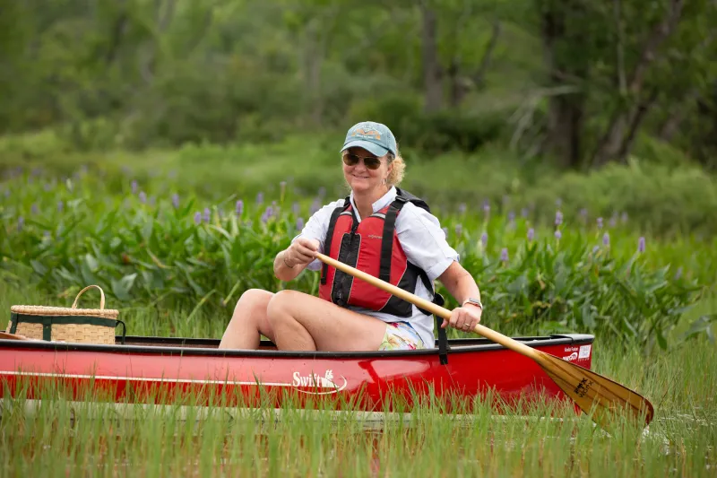 Woman paddling a canoe through flowers