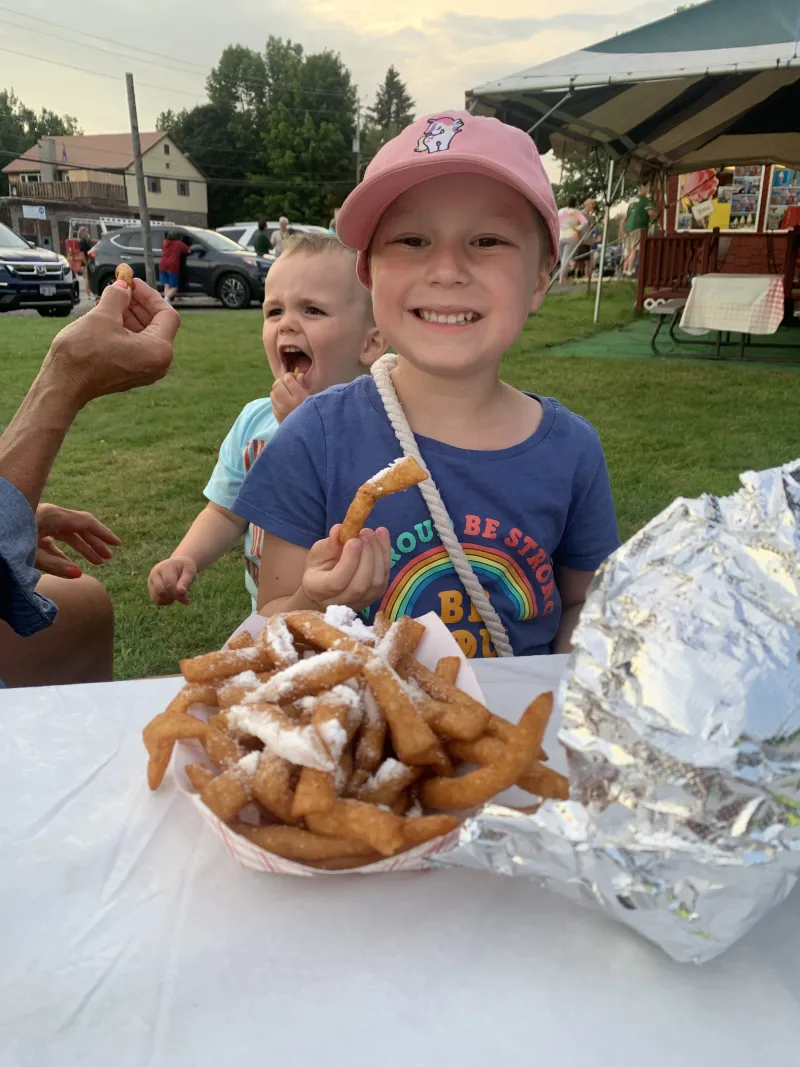 A girl enjoys funnel cake fries at a picnic table outside of Skyline.