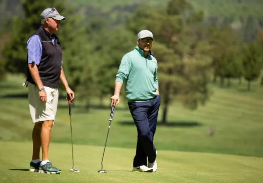 To golfers chat as they stand on the course.