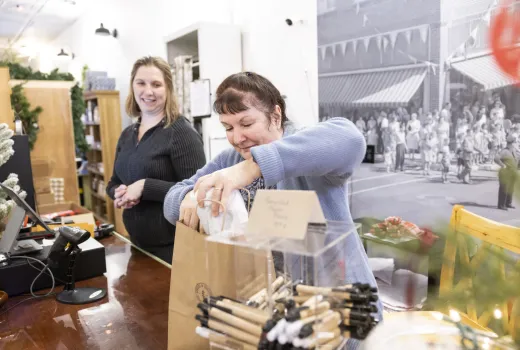 Two women package a purchase at a vintage counter. 