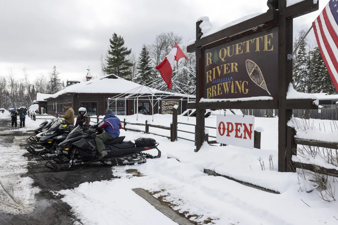 Snowmobiles parked outside Raquette River Brewing in Tupper Lake.