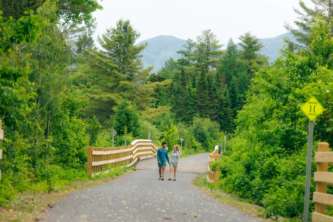 A young couple holds hands on a gravel trail.