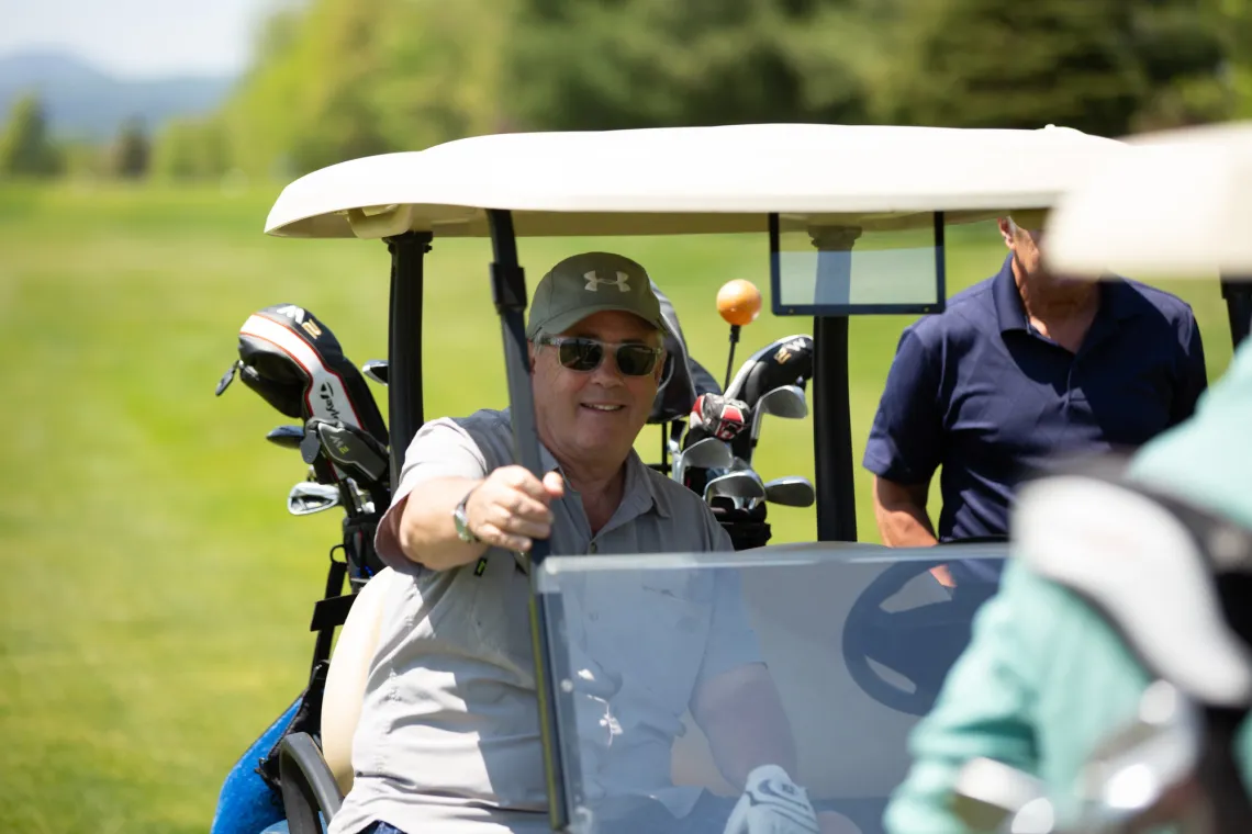 Golfer in a cart smiles at the camera.