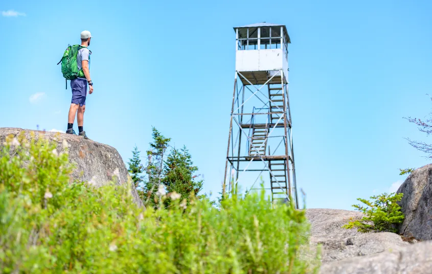 A hiker looks up at a firetower