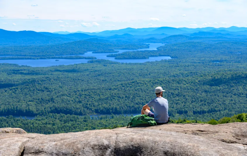 A hiker enjoying the views from a cliff on St Regis Mountain