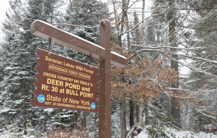 A wooden sign for Deer Pond in the winter