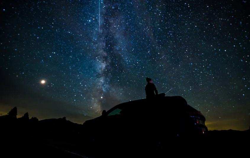 A person on their car stargazing