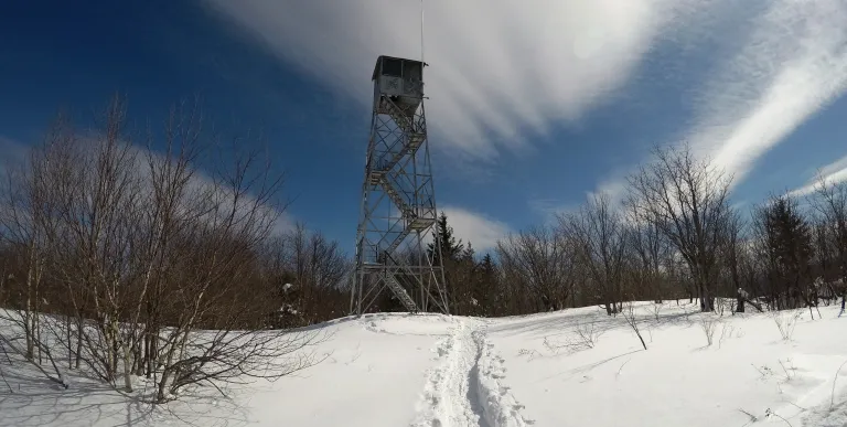 A firetower in the winter with wispy clouds above