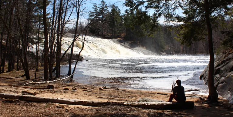 A waterfall by a flat shoreline