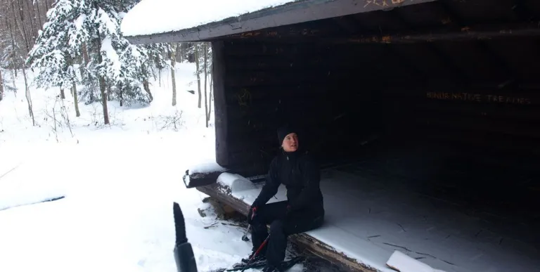 A person sits in a lean-to in the winter