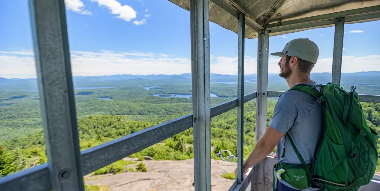 A hiker standing in the firetower cab of St Regis Mountain