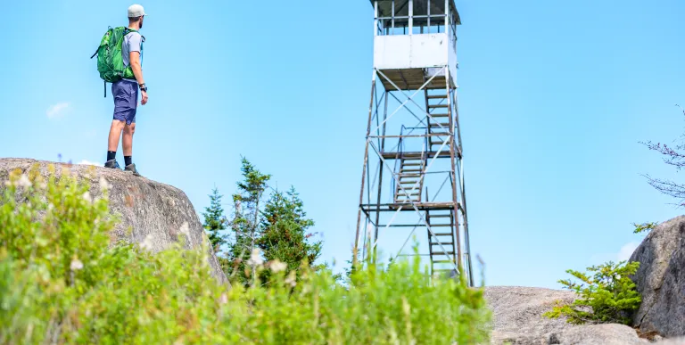 A hiker looks up at a firetower