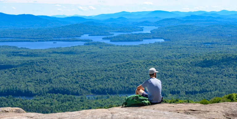 A hiker enjoying the views from a cliff on St Regis Mountain